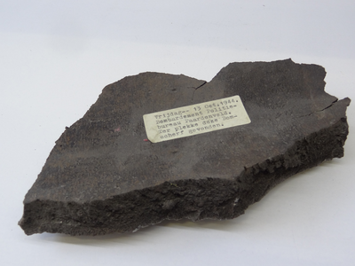 878140 Afbeelding van een bomscherf gevonden bij het Hoofdbureau van Politie op het Paardenveld in Wijk C, na het ...